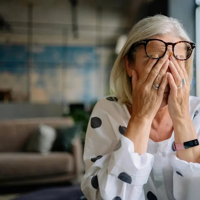 A woman at her desk rubbing her eyes, overwhelmed by scattered health information